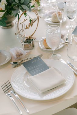 Şık bir yemek masası zarif bir toplantı için porselen, gümüş çatal bıçak ve çiçek süsü ile süslenir..