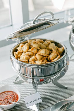 Enfes bir yengeç rangoonu şık bir modern etkinlikte soslu şık bir yemek tabağında sunuluyor..