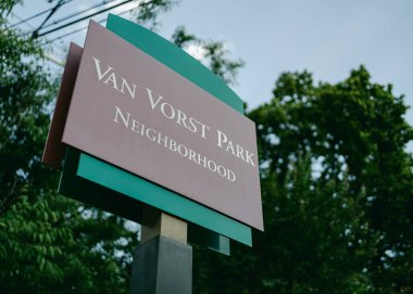 Park tabelası Van Vorst Parkı 'nın girişini gösteriyor. Gündüz vakti Jersey' de yemyeşil bir alan var..