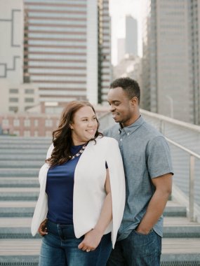 Bir çift, yüksek binalar ve şehir hayatı ile çevrili bir şehir merdiveninde neşeli bir anı paylaşıyor..