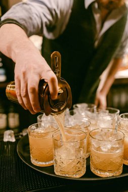Barmen, bir gece barında konuklar için bardaklara taze içecekler doldurur ve canlı bir atmosfer yaratır..