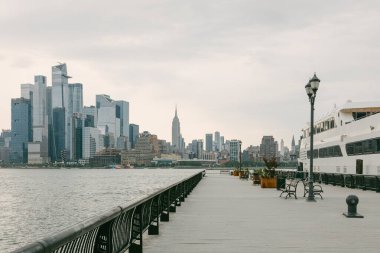 Rıhtım güvertesi New York şehrinin gökyüzü bulutlu ve kenetlenmiş gemileriyle gökyüzünü gösteriyor..
