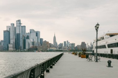Rıhtım güvertesi New York şehrinin gökyüzü bulutlu ve kenetlenmiş gemileriyle gökyüzünü gösteriyor..