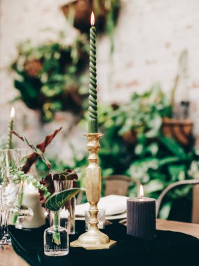 Güzel bir masada yeşil bir mum, zarif bir cam eşyalar ve samimi bir yemek için canlı bitkiler sergilenir..