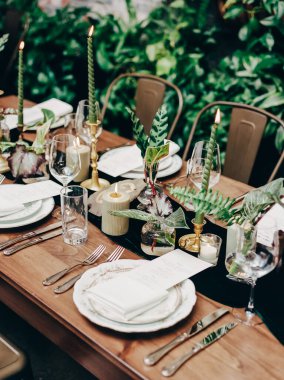 Çok güzel düzenlenmiş bir yemek masasında mumlar ve taze bitkiler vardır. Arkadaşlarla unutulmaz bir etkinlik için mükemmeldir..