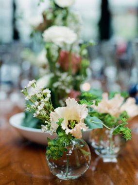 Güzel çiçek aranjmanları özel bir durum için yemek masasında yumuşak renkler ve yeşillik içerir..