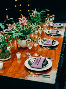 Mor peçeteler, cam eşyalar ve çiçek dekoru ile güzel bir yemek masası şenlik havası yaratır..