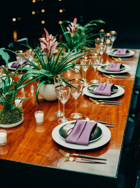 Mor peçeteler, cam eşyalar ve çiçek dekoru ile güzel bir yemek masası şenlik havası yaratır..