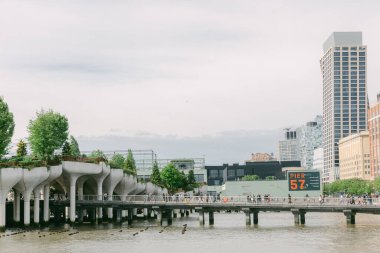 Ziyaretçiler, modern mimari ve yemyeşil alanlarla çevrili iskele boyunca sakin bir şekilde yürümekten hoşlanıyorlar..
