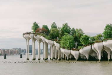 Ziyaretçiler, bereketli ağaçlar ve şehir manzarasıyla çevrili modern parkın sularına tünemiş manzaralı bir inzivaya çekiliyorlar..