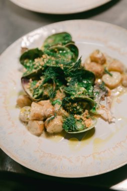Canlı bir deniz ürünleri tabağı kabuklu deniz ürünleri, gnocchi ve sıcak, davetkar bir ortamda otlarla kaplıdır..