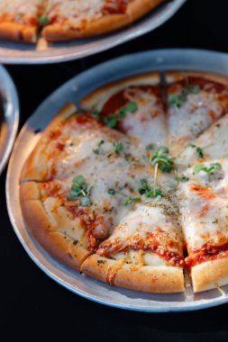 Metal tepside otlarla süslenmiş taze pişmiş peynirli pizza. Rahat bir atmosferde rahat bir yemek için mükemmel..