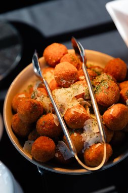 Bitki ve sosla kaplı gevrek böreklerle dolu bir kase, canlı bir akşam yemeği etkinliğinde eğlenmeye hazır..