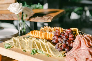 Güzelce hazırlanmış bir tabakta gurme peynirler, taze üzümler ve gün içinde bir sosyal etkinlikte pişirilmiş etler yer alıyor..