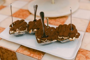 Klasik bir tatlının zevki için gümüş kaşıklarla hazırlanmış bir tabakta servis edilmesi..