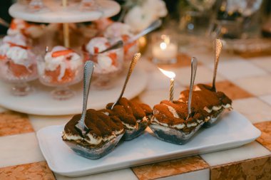 Çok güzel hazırlanmış bir tatlı masası tiramisu ve meyve tabakları bir akşam yemeğinde mumlarla süslenmiş..