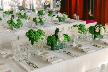 Taze çiçekler ve güzel yemek malzemeleriyle süslenmiş masalar özel bir toplantı için sofistike bir ortam yaratır..