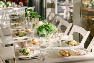 Salatalar, su bardakları ve toplanma için taze sebzelerle dolu uzun bir masa seti..