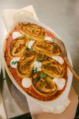 Et ve otlarla dolu baharatlı börekler taze otlarla süslenmiş canlı domates sosuyla güzelce düzenlenir..