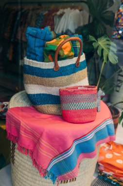 Yerel bir zanaatkarlığın sergilendiği parlak bir masanın üzerine örülmüş renkli çantalar ve kumaşlar..