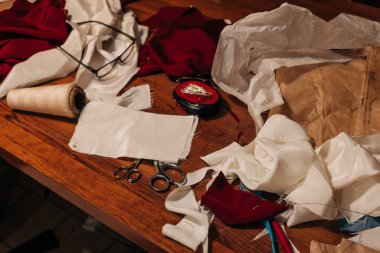 Dağınık kumaş, makas ve dikiş aletleriyle dolu bir zanaat istasyonu yaratıcı bir süreç sunuyor.