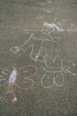 Çubuk figürünün tebeşir çizimleri ve kelebekler parlak bir günde betonu süsler, yaratıcılığını sergiler..