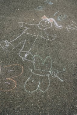 Tebeşir sanatında neşeli bir çocuk figürü, güneşli bir günde tuhaf bir kelebeğin yanında bulunur..