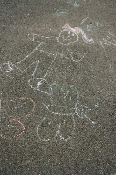 Tebeşir sanatında neşeli bir çocuk figürü, güneşli bir günde tuhaf bir kelebeğin yanında bulunur..