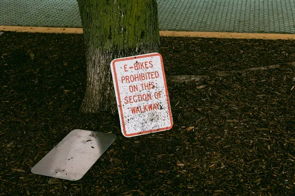 Yürüme yolundaki bir ağacın yanında durmanın yasak olduğunu belirten bir tabela, bölgede yaya güvenliğini sağlıyor..