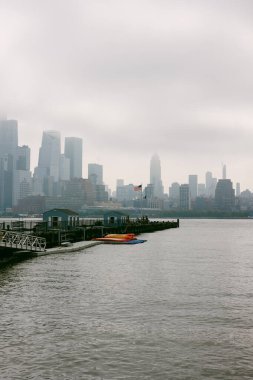 Bulutlu hava, liman boyunca bir limana demirlemiş teknelerle bir şehrin ufuk çizgisini sarıyor..