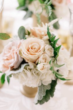 Güzel çiçek aranjmanı yumuşak pembe ve kremalı güller, verimli bir toplantıda yemyeşil ile çevrili..