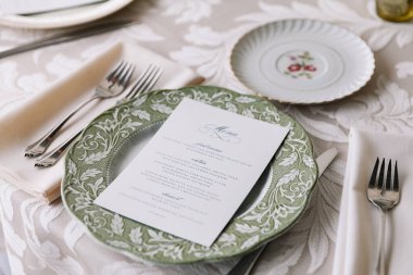 Resmi bir yemek masası, nefis tabaklar, çatal bıçak takımı ve zarif bir menü kartı..