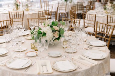 Çiçekler ve camlarla süslenmiş zarif masalar kutlama için hoş bir ortam hazırladı..