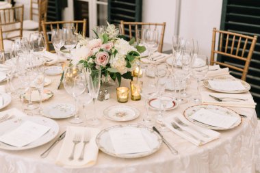 Güzel düzenlenmiş bir masa, cam süsleme ve güzel aydınlatılmış bir etkinlik alanında bir çiçek süsü..