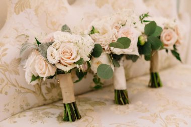 Üç güzel gül buketi yumuşak kumaşa dizilir, narin çiçek sanatını ön plana çıkarırlar..