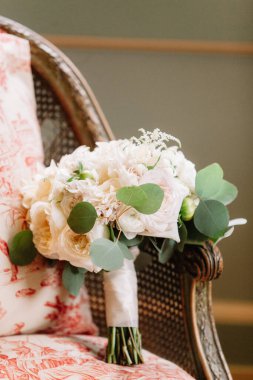 Beyaz güller ve yeşillik içeren güzel bir gelin buketi eski bir sandalyeye yerleştirilir ve seremoniyi bekler..