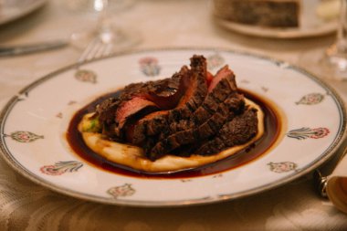 Çok güzel sunulan bir et tabağında, bol soslu kremalı patates püresi üzerinde taze et bulunuyor..