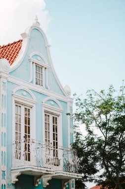 Sömürge mimarisi, renkli mavi bir cephe, karmaşık detaylar ve yemyeşil bir ortamda büyüleyici bir balkon sergiliyor..