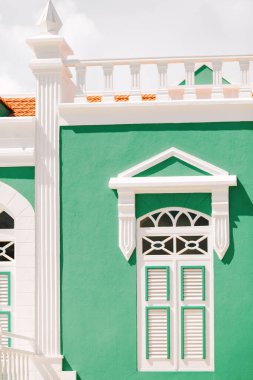 Beyaz süslemeli çarpıcı yeşil bir bina Karayip mimari güzelliğini gün ışığında sergiliyor..