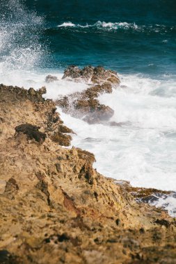 Güçlü dalgalar engebeli kayalara çarpar ve sahil boyunca doğanın çarpıcı gücünü gösterir..