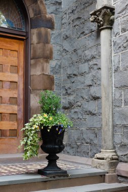 Renkli çiçekler ve yeşillik büyüleyici taş bir kapı girişinden taşarak mimari cazibeyi artırıyor..