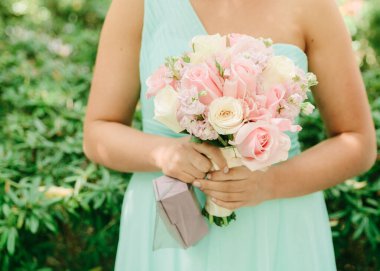 Bir nedime kutlama yaparken canlı bir bahçe ortamında pastel renkli bir buket çiçek tutar..
