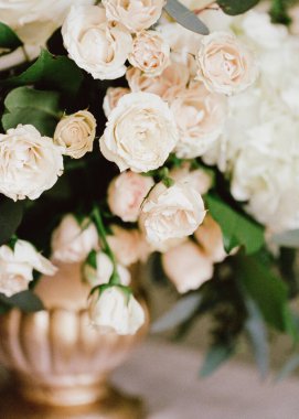 Zarif güller ve yeşillikler şık bir vazoda göz kamaştırıcı bir çiçek sergisi oluşturur. Etkinliklerde dekorasyon için mükemmeldir..