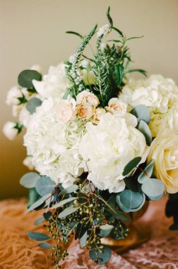 Bir vazoda güzel bir çiçek ve yeşillik karışımı, düğün ve etkinlikler için mükemmel, doğal bir zarafet sergiliyor..