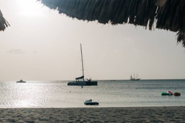 Güneş ufukta batarken, sakin sularda dinlenen yelkenliler sakin bir atmosfer yaratıyor..