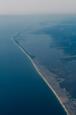Geniş kıyı şeridi ufuk boyunca uzanıyor, kumlu plajlar ve karaya vuran dalgalar sergiliyor..