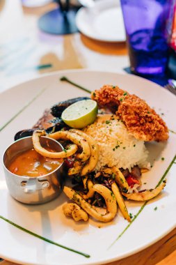 Renkli tabaklar kızarmış tavuk, ızgara kalamar, pirinç ve limonla süslenmiş sos..