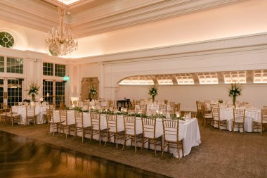 Çok güzel hazırlanmış bir ziyafet salonunda çiçeklerle süslenmiş masalar var. Kutlama için hazırlar..