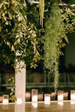 Yeşil yapraklar ve yosunlar zarif bir şekilde sarkıyor. Yumuşak titreyen mumlar, sakin ve samimi bir yerde..