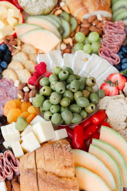 Renkli bir meyve, peynir ve pişirilmiş et çeşidi büyük bir tabakta büyük bir tabakta sunuluyor..
